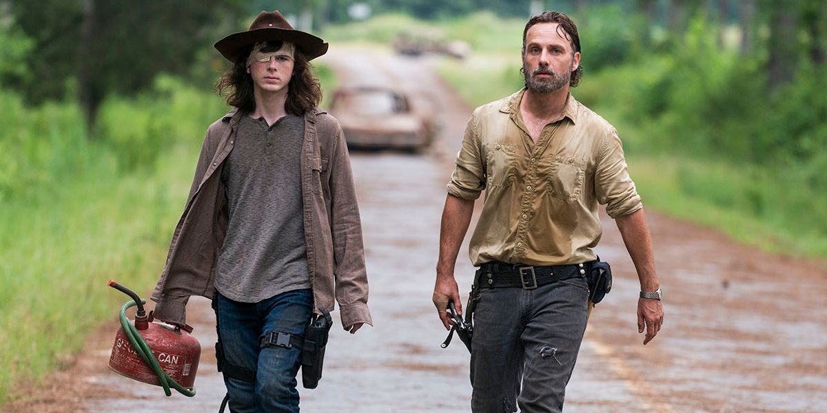 Carl (Chandler Riggs) lleva un tanque de gasolina mientras camina junto a Rick (Andrew Lincoln) en The Walking Dead.