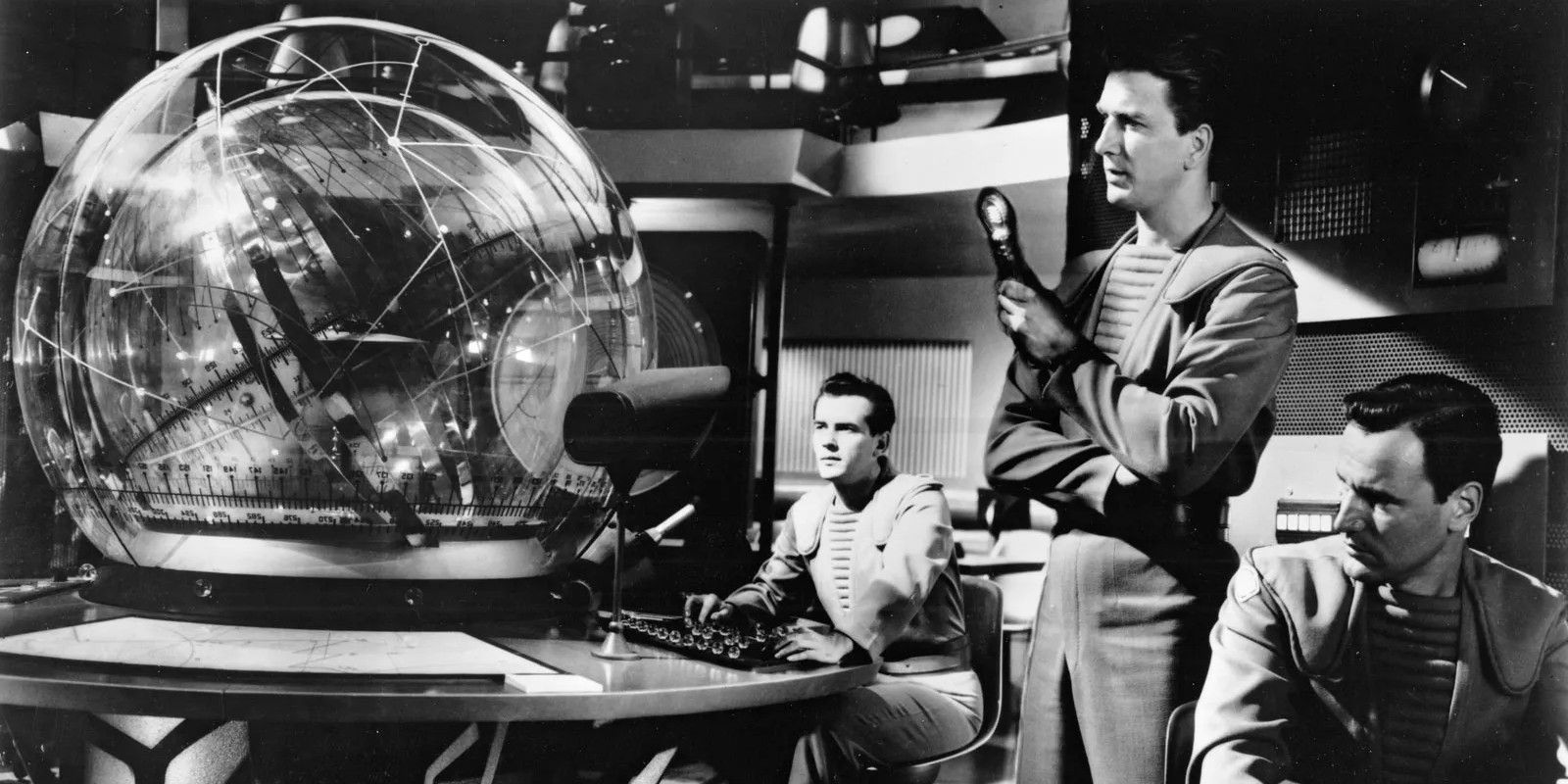 Tres hombres en una sala de control futurista en The Forbidden Planet
