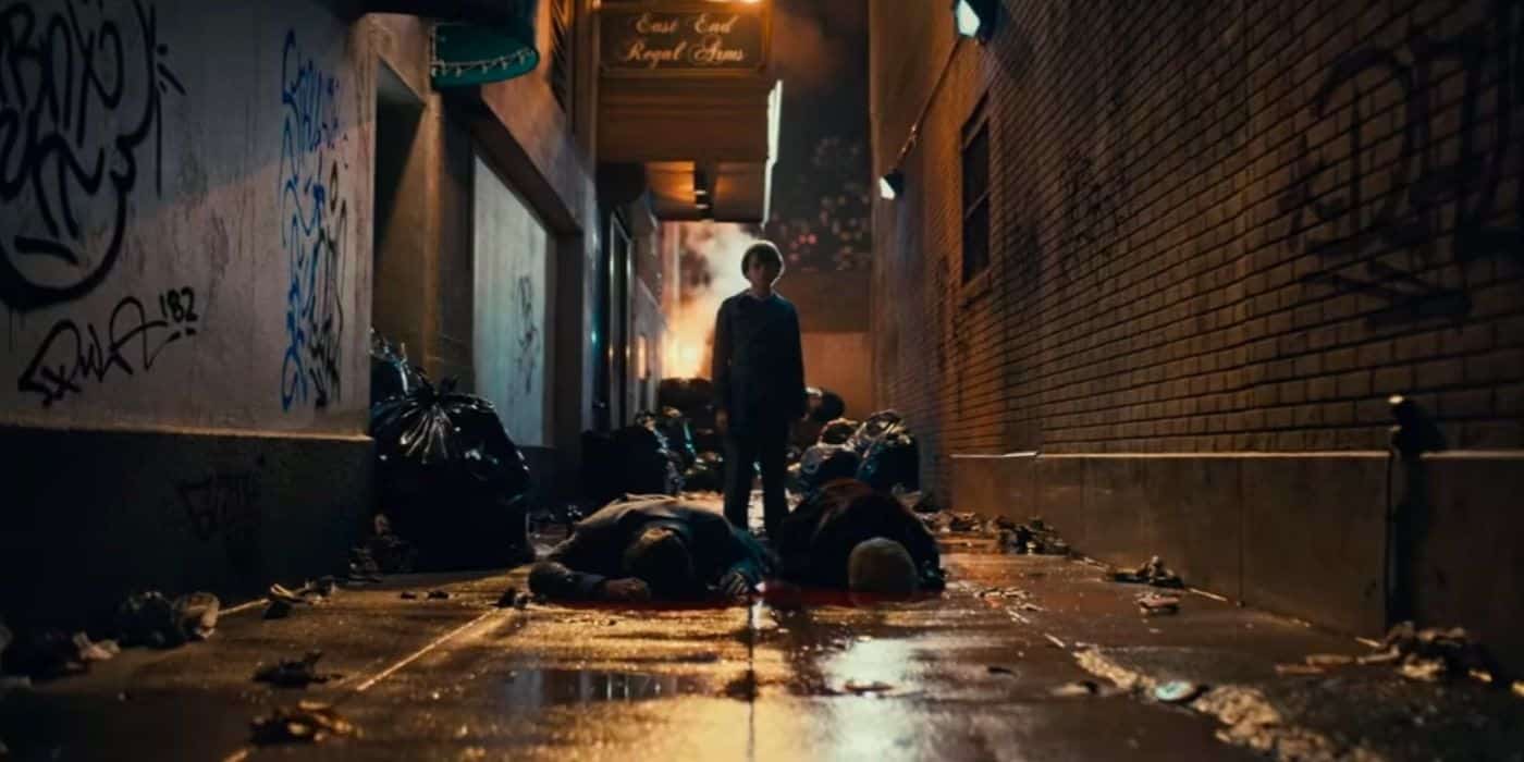 Un joven Bruce Wayne junto a los cuerpos de sus padres, que yacían en un callejón