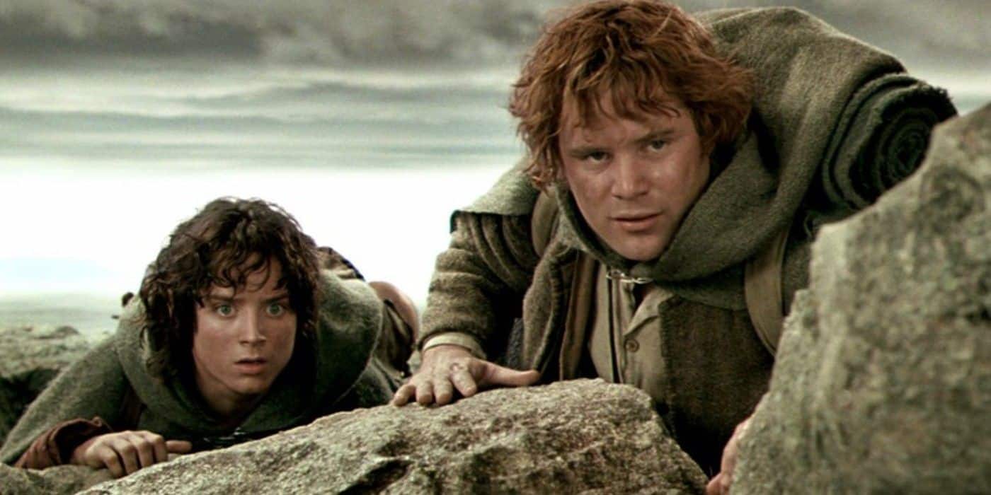 Frodo y Sam se agachan detrás de unas rocas y miran la Puerta Negra en El Señor de los Anillos.