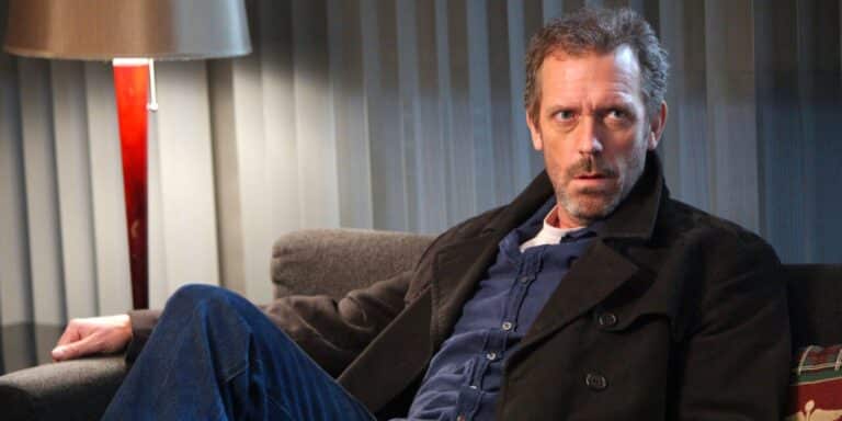 Hugh Laurie sits on a couch in House MD