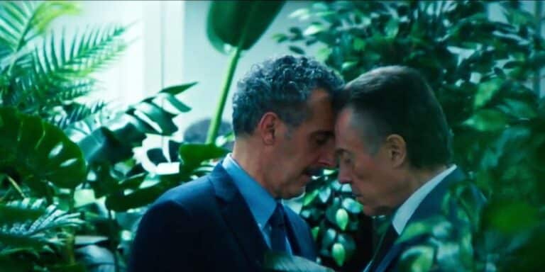 Irving y Burt con la frente juntos, ojos cerrados en el jardín rodeado de arbustos de despido.