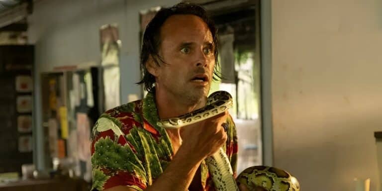 Walton Goggins sosteniendo una serpiente en el loto blanco.