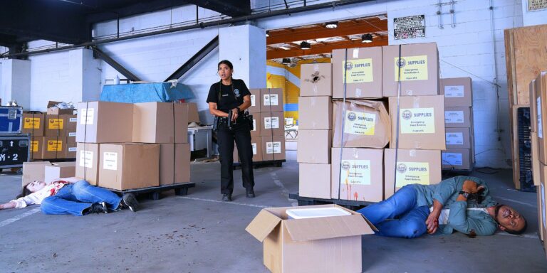 Celina Juarez, in the police, bdus holding between two boxes while Kylie Thomas and James Murray are on the ground, bloody on each side of the recruit