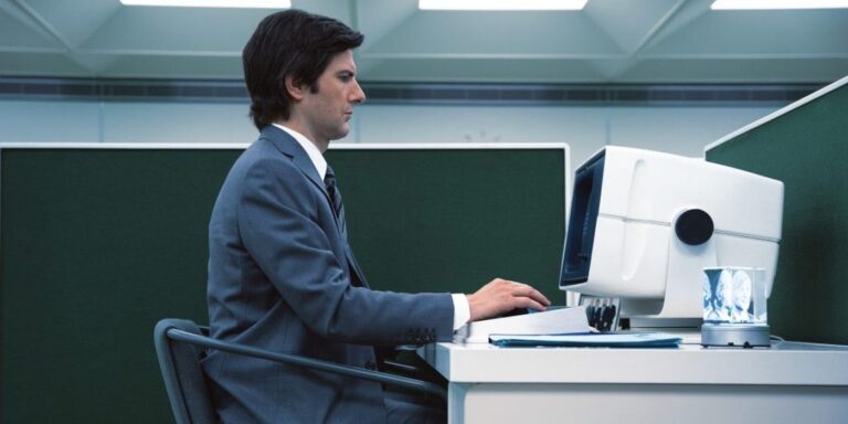 Mark sentado en su computadora trabajando en una oficina indescriptible de severidad.