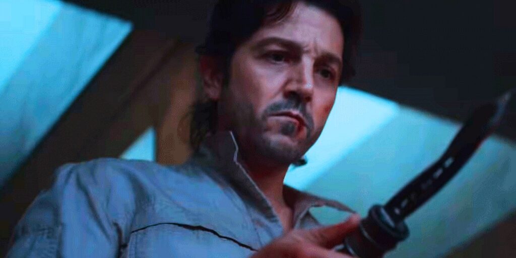 Close -up of Cassian Andor in a gray blue shirt holding a twisted knife