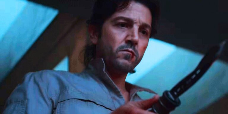 Close -up of Cassian Andor in a gray blue shirt holding a twisted knife