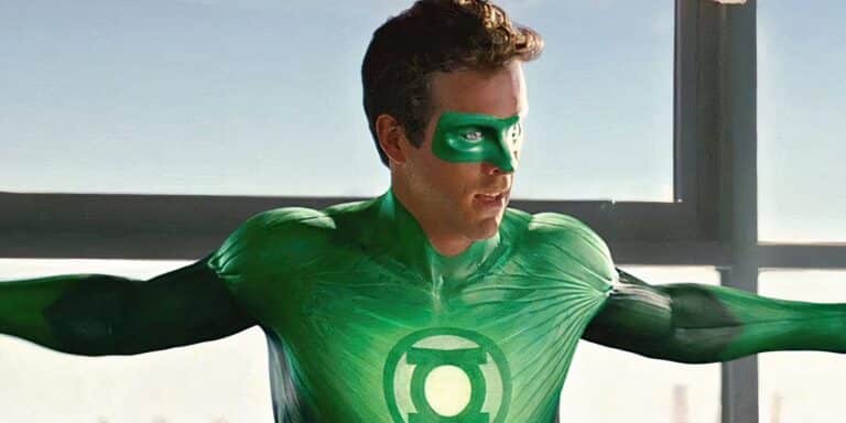 Ryan Reynolds como Hal Jordan frente a una ventana que se extiende con los brazos en su disfraz en la película Green Lantern.