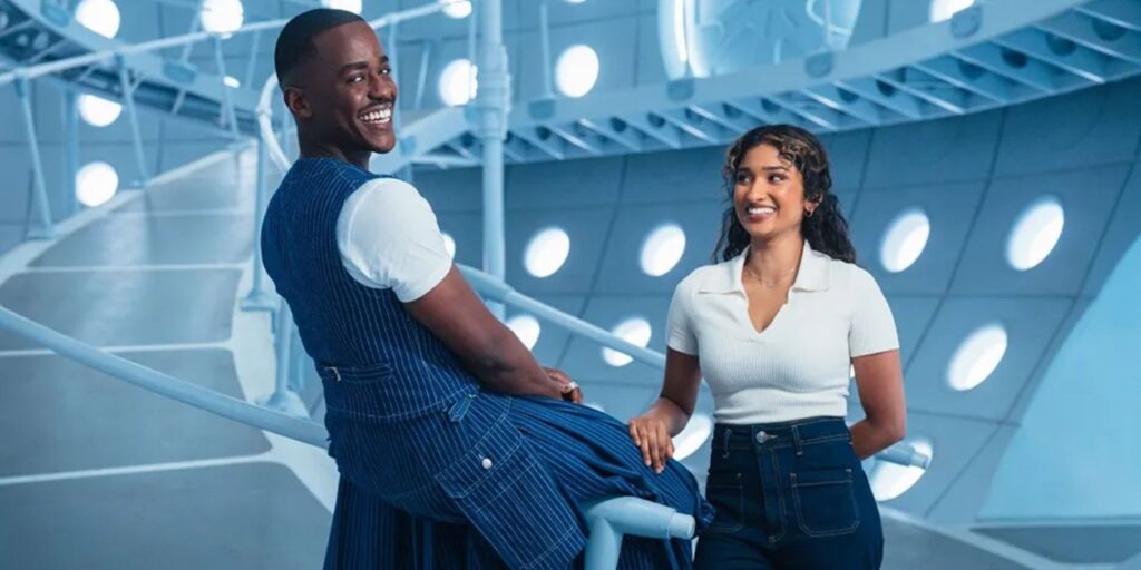 The doctor carrying a blue vest, standing in the Tardis with Belinda Chandra of Doctor Who Season 2