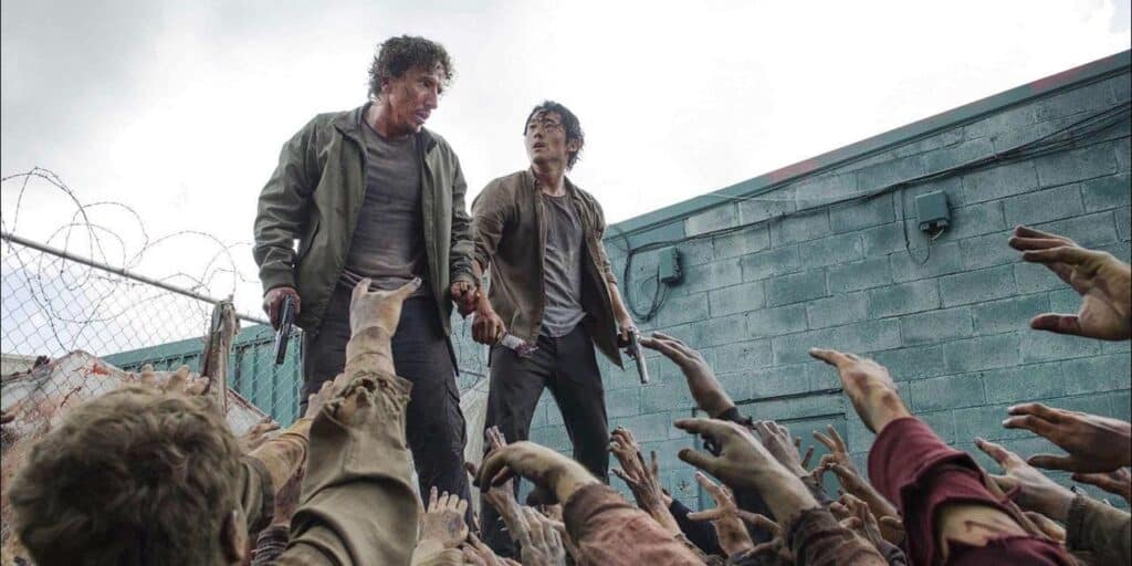 Nicholas y Glenn en la parte superior de un contenedor rodeados de caminantes en los muertos.