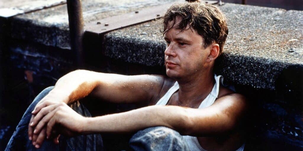 Andy Dufresne sits against a wall in the prison court in the redemption of Shawshank 1994-1