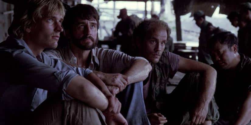 Four men sit on the ground in the killings fields.