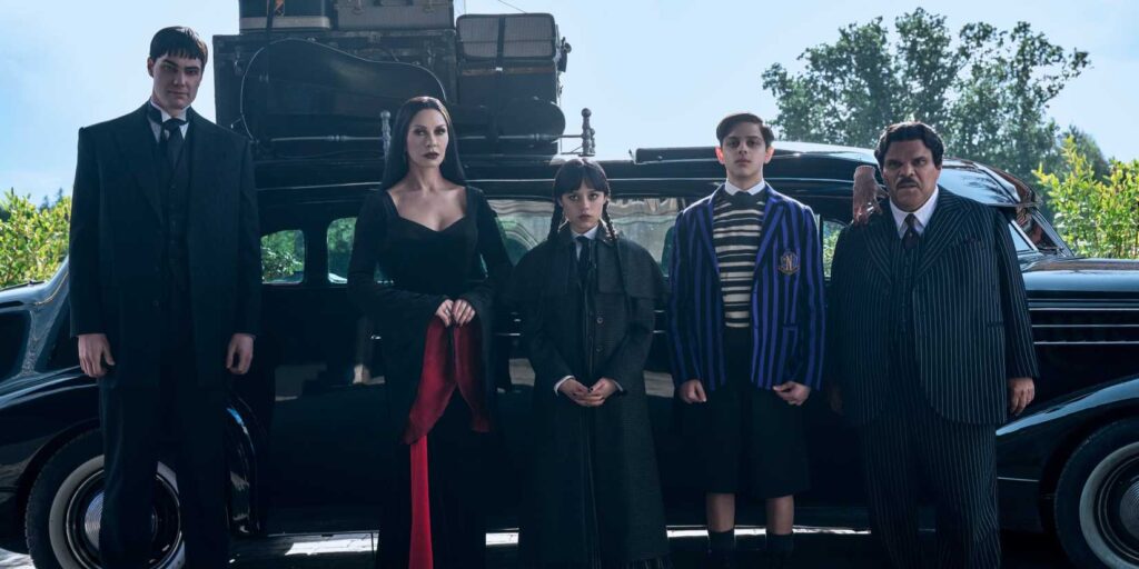 LURCH, MORTICIA, Wednesday, Pugsley, Thing and Gomez Addams standing near their car on Wednesday season 2.